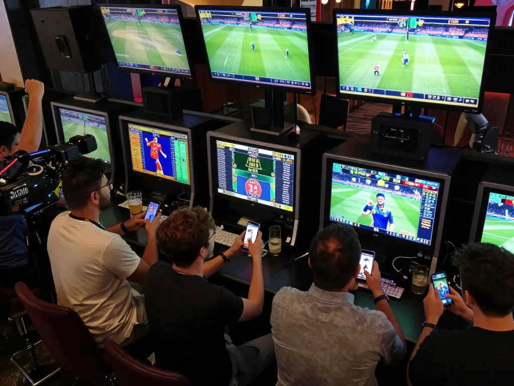 Winbd users engaging in thrilling sports betting at a lively venue, screens showing live matches and friends celebrating.