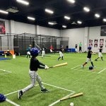 Hitclub baseball training session with young athletes practicing hitting techniques in dynamic indoor environment.