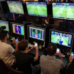 Winbd users engaging in thrilling sports betting at a lively venue, screens showing live matches and friends celebrating.